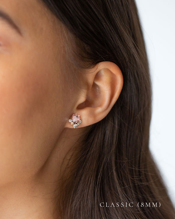A closeup of a model wearing our Celestial Crystal Cluster Earrings in gold with blush crystals in the classic 8mm size.
