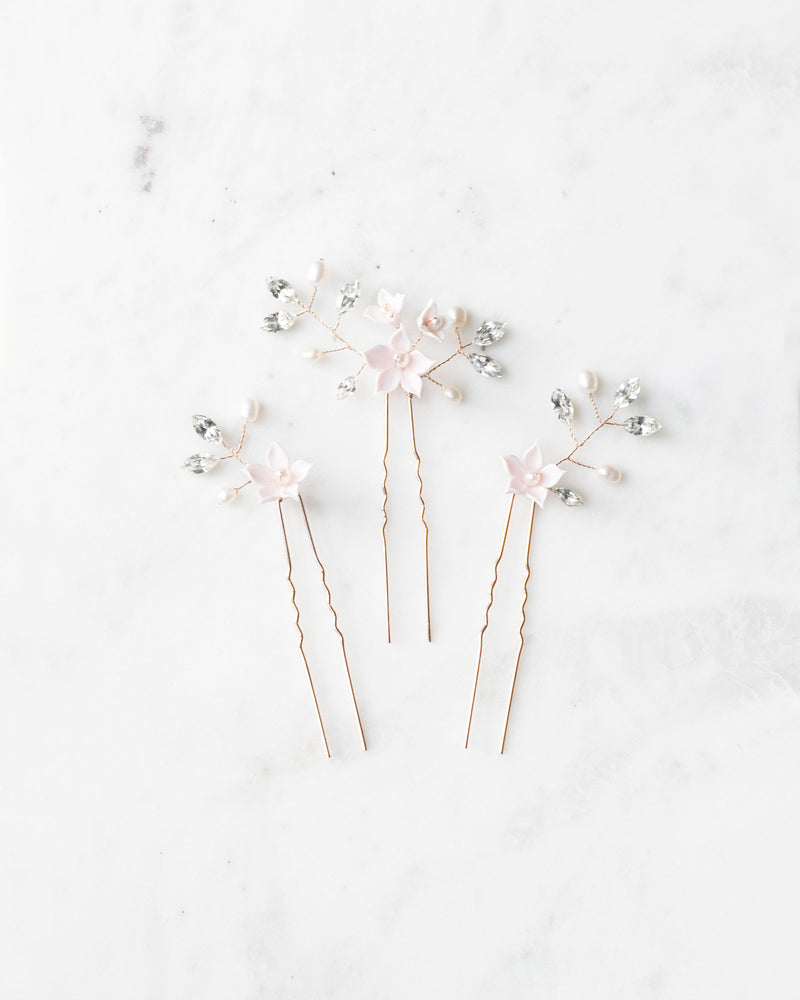A flatlay view of the trio of Belle Fleur Hair Pins. The pins are gold, with ivory flowers, pearls, and crystals.