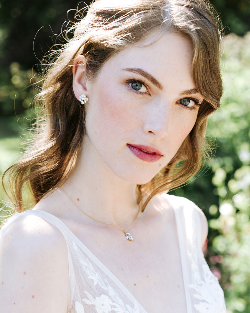 A model gazes into the camera. Here hair is down and she is wearing a jewelry set with crystal stud earrings and a delicate gold necklace with a crystal drop.