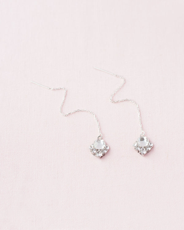 A flatlay view of the Celestial Crystal Threader Earrings in silver/crystal.