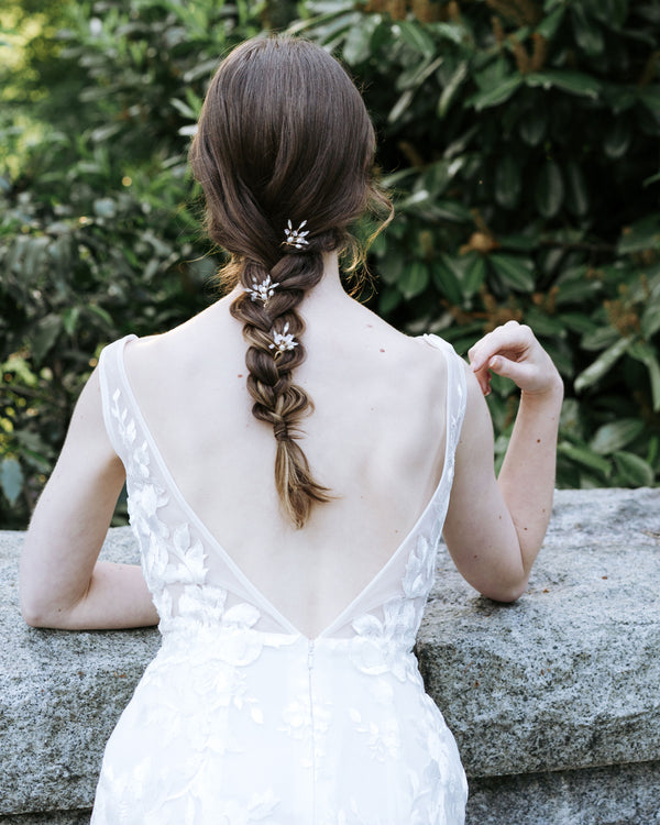 A bride wears a trio of bridal hair pins in her bridal braid. The hair pins have crystals, pearls, and moonstone gemstones.