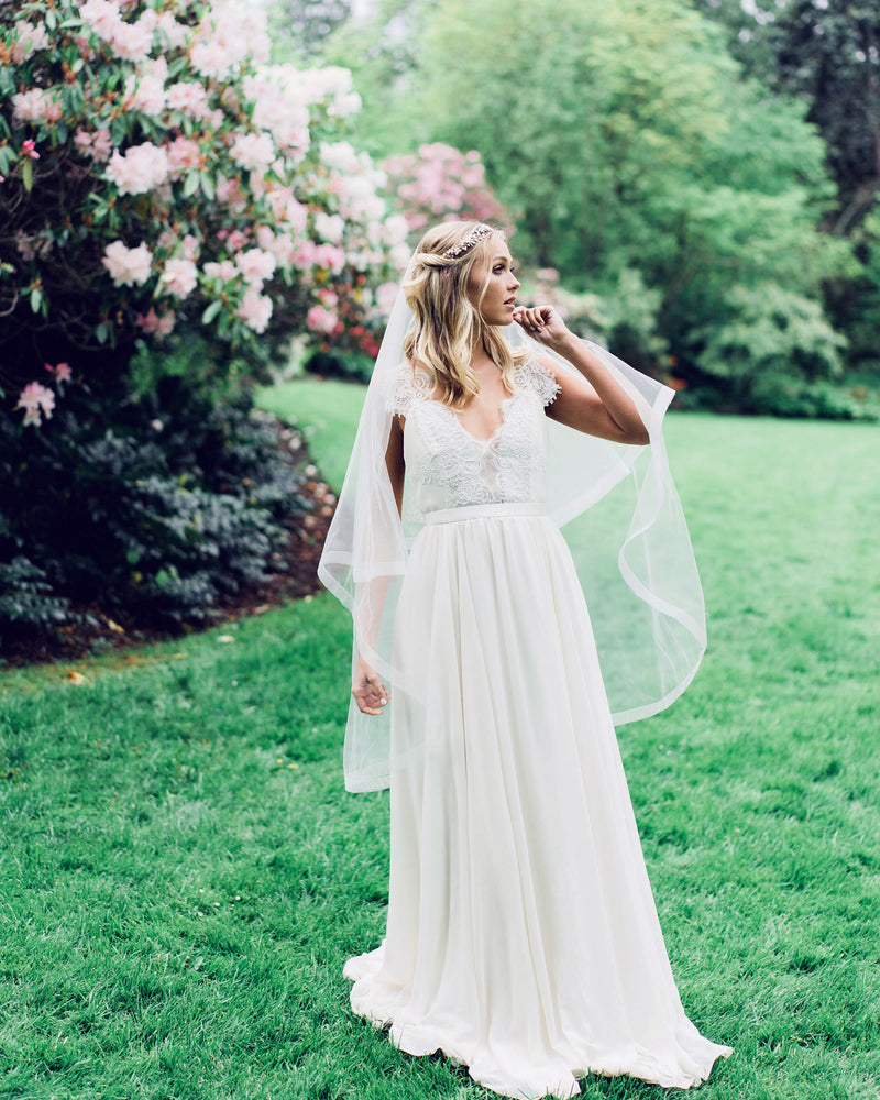 A bride wears the Zahra Horsehair Trim Veil in fingertip length, with the blusher worn to the back.