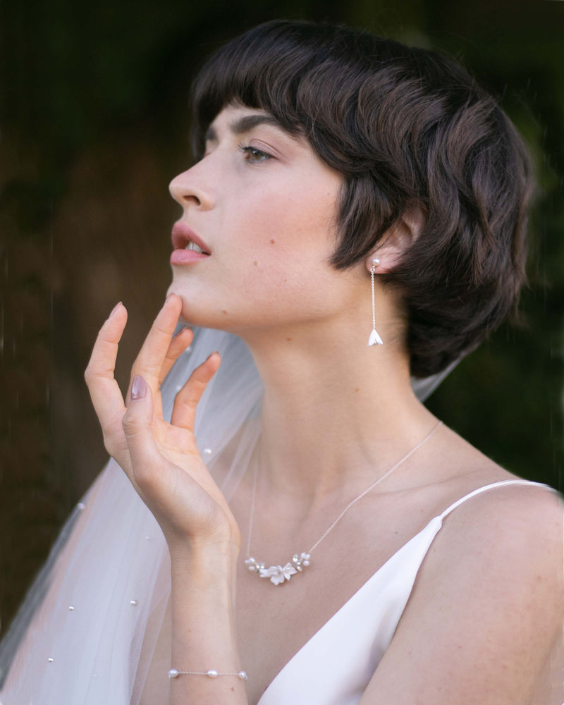 A bride wears the Belle Fleur Long earrings in silver with matching Belle Fleur Necklace and dainty pearl bracelet.
