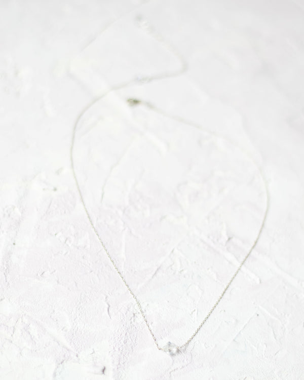 Flatlay view of the Prism Necklace; a single crystal drop on a delicate chain.
