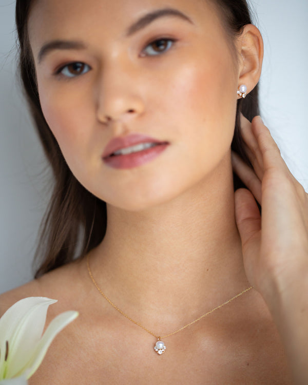 A bridesmaids wears the Celestial Pearl Petite Jewelry Set in gold.