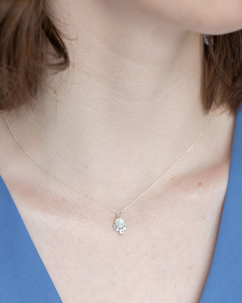 A close view of a model wearing the petite version of the Celestial Crystal Drop Necklace in silver with white opal crystals.