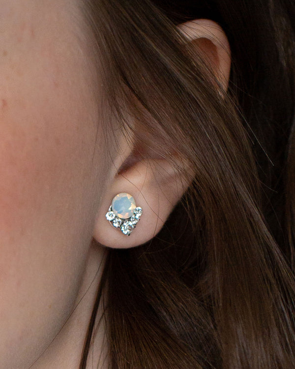 A close view of a model wearing our Celestial Crystal Cluster Earrings in silver with white opal crystals.