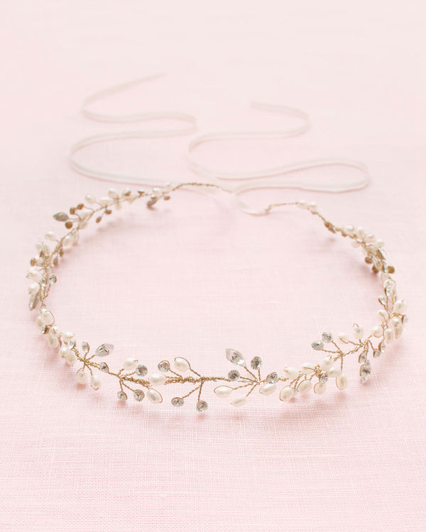 Flatlay of a delicate gold hair vine made of crystals, pearls, and dainty pearl flowers.