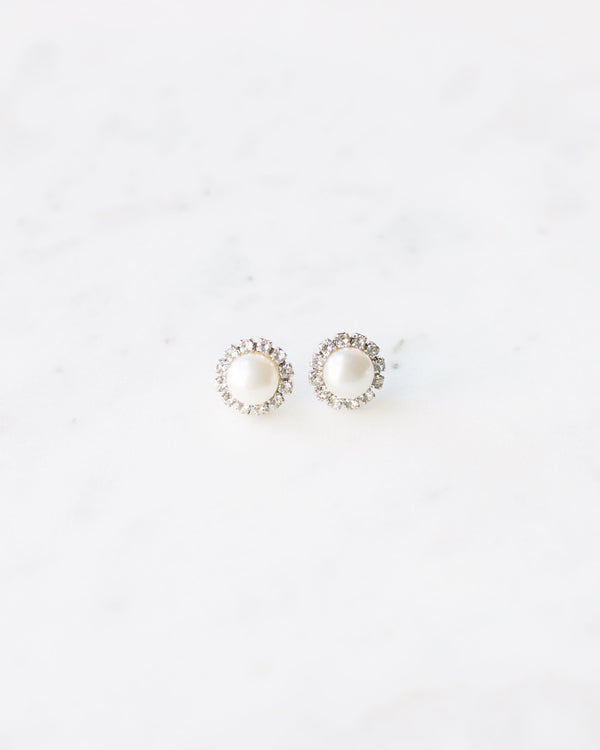 Flatlay of the Halo Pearl Stud Earrings; freshwater pearls surrounded by a halo of crystals.