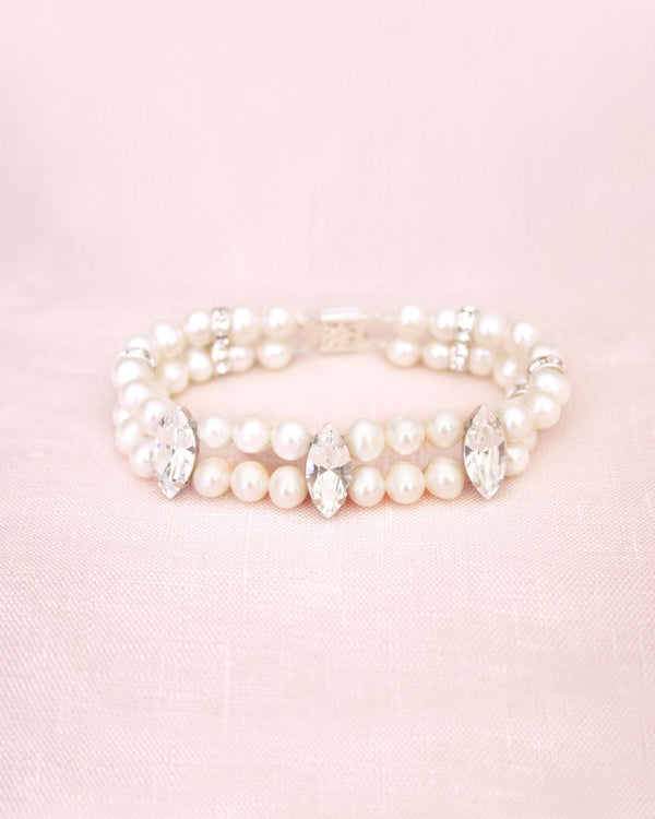 Flatlay on pink background of a double strand pearl wedding bracelet with marquise crystals.
