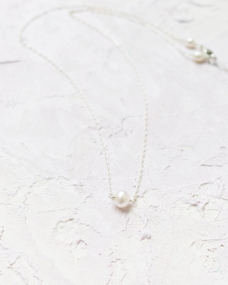 Flatlay of the Pearl Drop Necklace in silver.