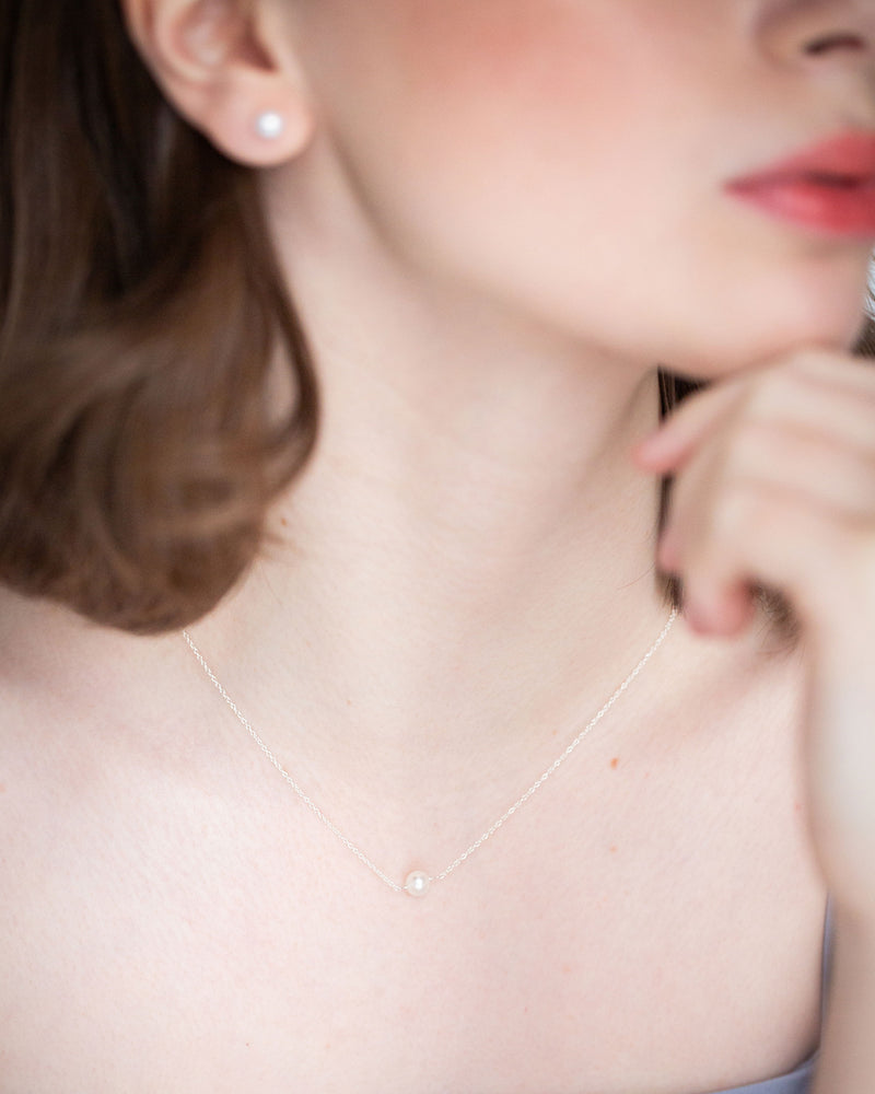 A model wears a wedding necklace with a single pearl drop.