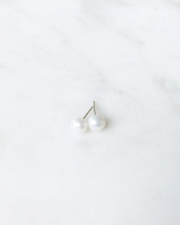 A flatlay view of the Pearl Stud Earrings in petite size, shown in silver.