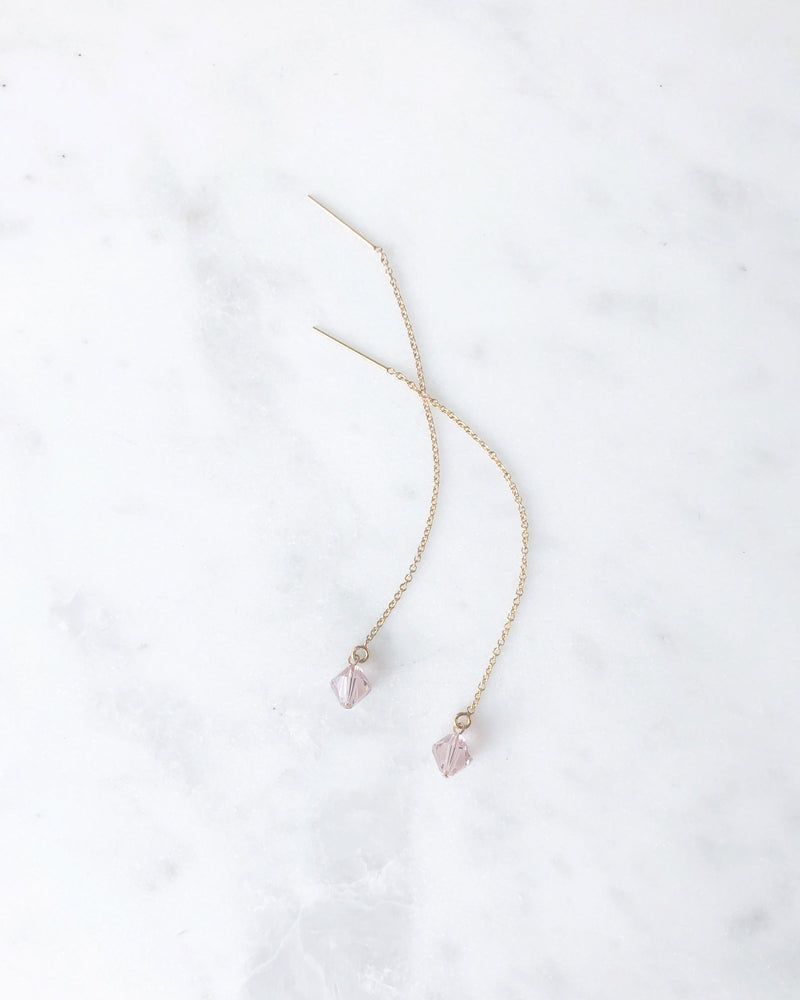 Flatlay of the Prism Threader Earrings in gold with blush crystals from our bridesmaid jewelry collection.