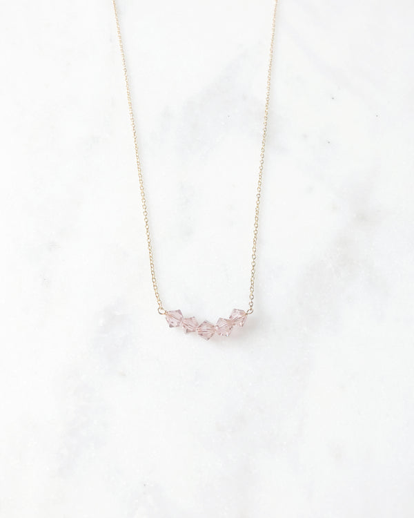 Flatlay of the Stardust Bridesmaid Necklace in gold with blush crystals.
