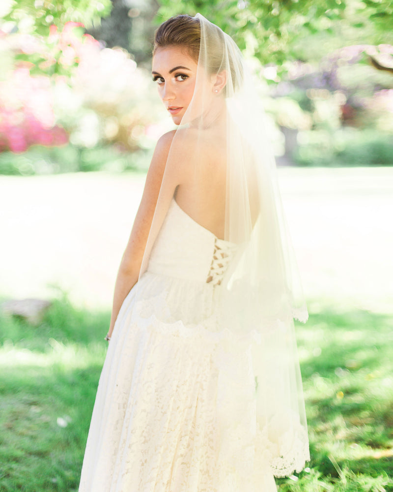 Back view of model wearing the Amara two-layer lace fingertip bridal veil with the blusher to the back.