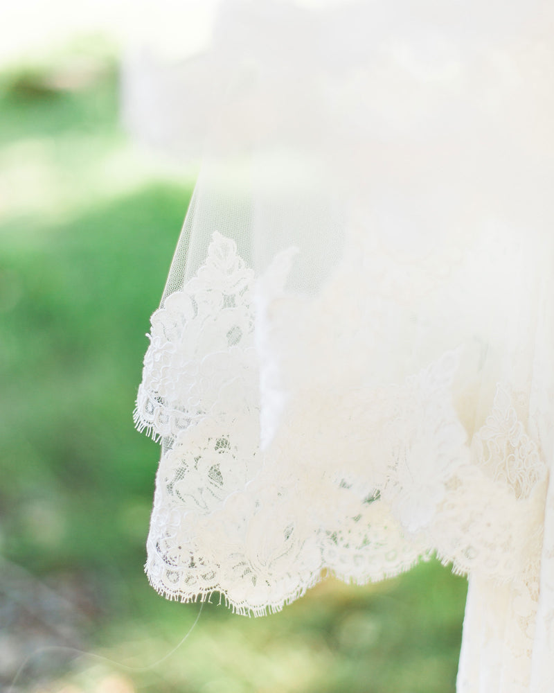 Close view on model of the lace edge on our Amara two-layer fingertip lace veil.