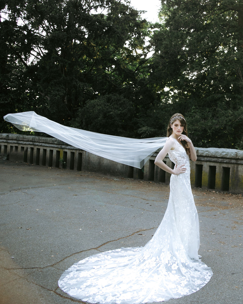 A model poses while the Aster Cape Veil floats in the air behind her.