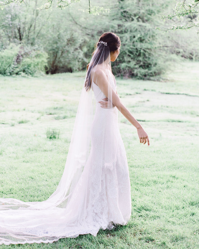 A dreamy faraway view of a model wearing the Aster Crystal Comb over her long veil.