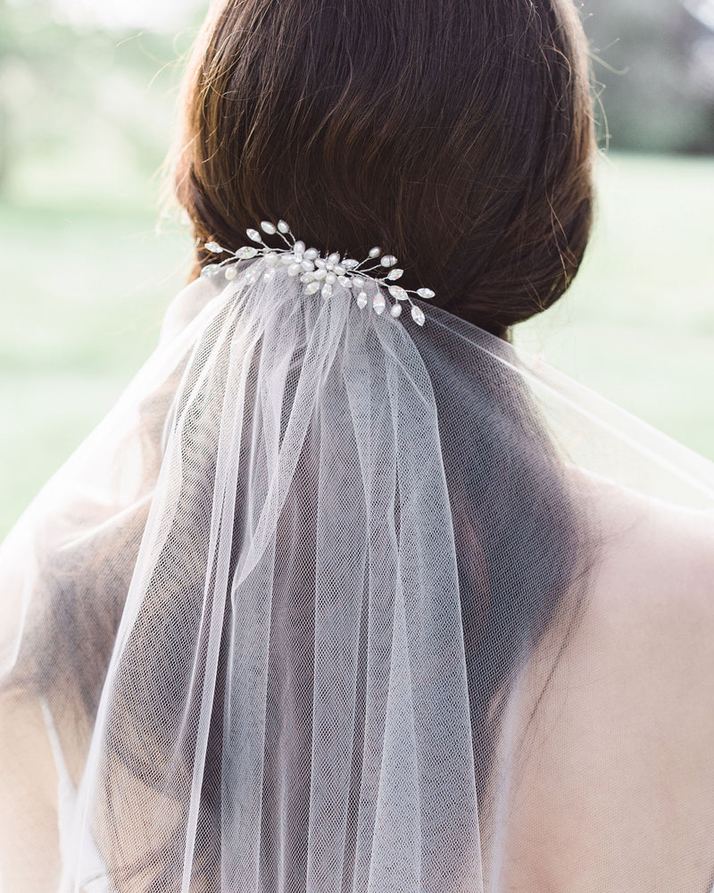 A model wears a wedding hair comb with pearls and crystals over her bridal veil.