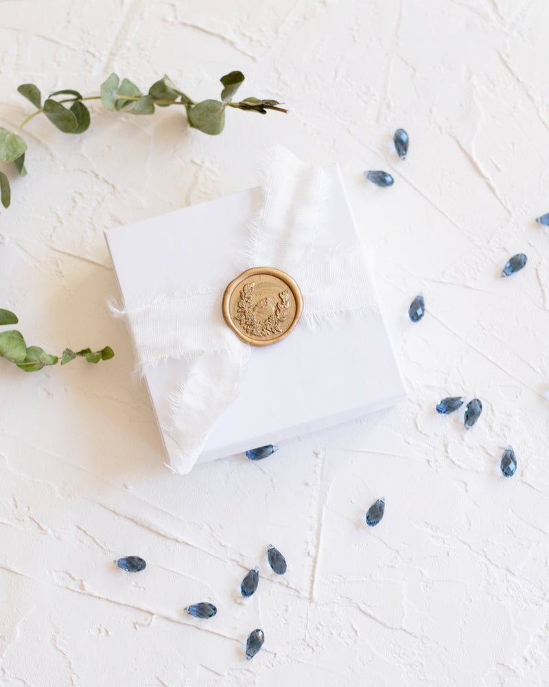 Flatlay of our Luxe Gift Wrapping with natural ribbon and gold wax seal.