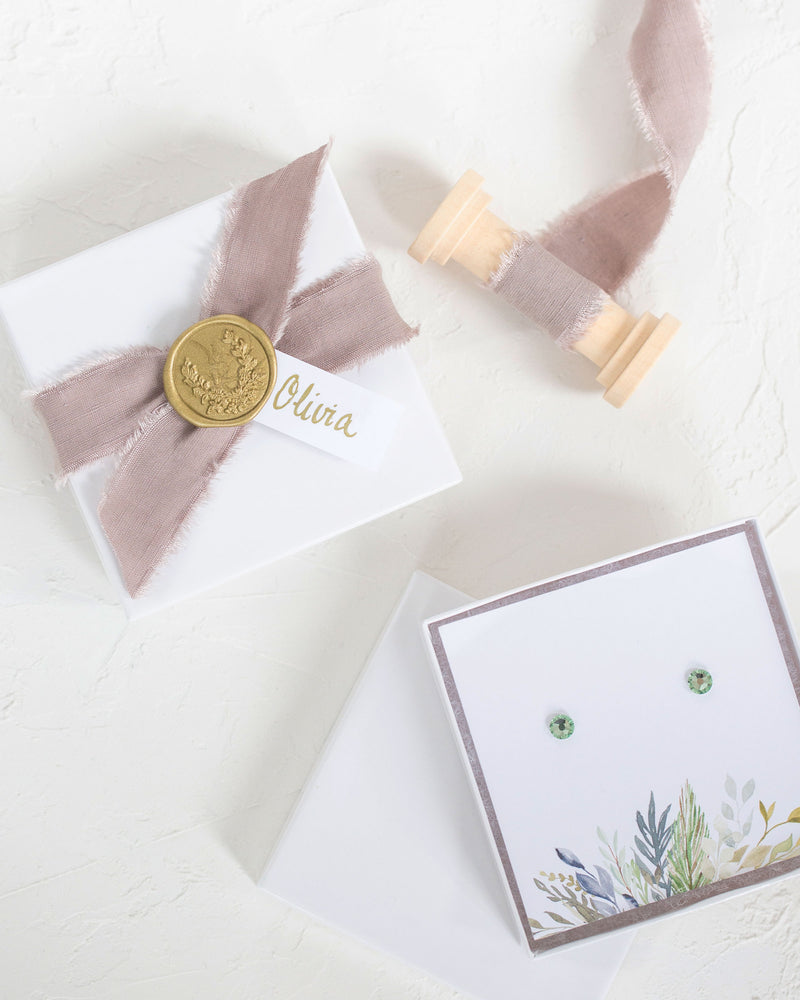 Flatlay of our Luxe Gift Wrapping with taupe linen ribbon, a gold wax seal and sage foliage jewellery box insert.