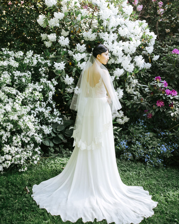 A model wears the Azalea two-layer veil with a lace border on bottom layer and soft blusher worn to the back.