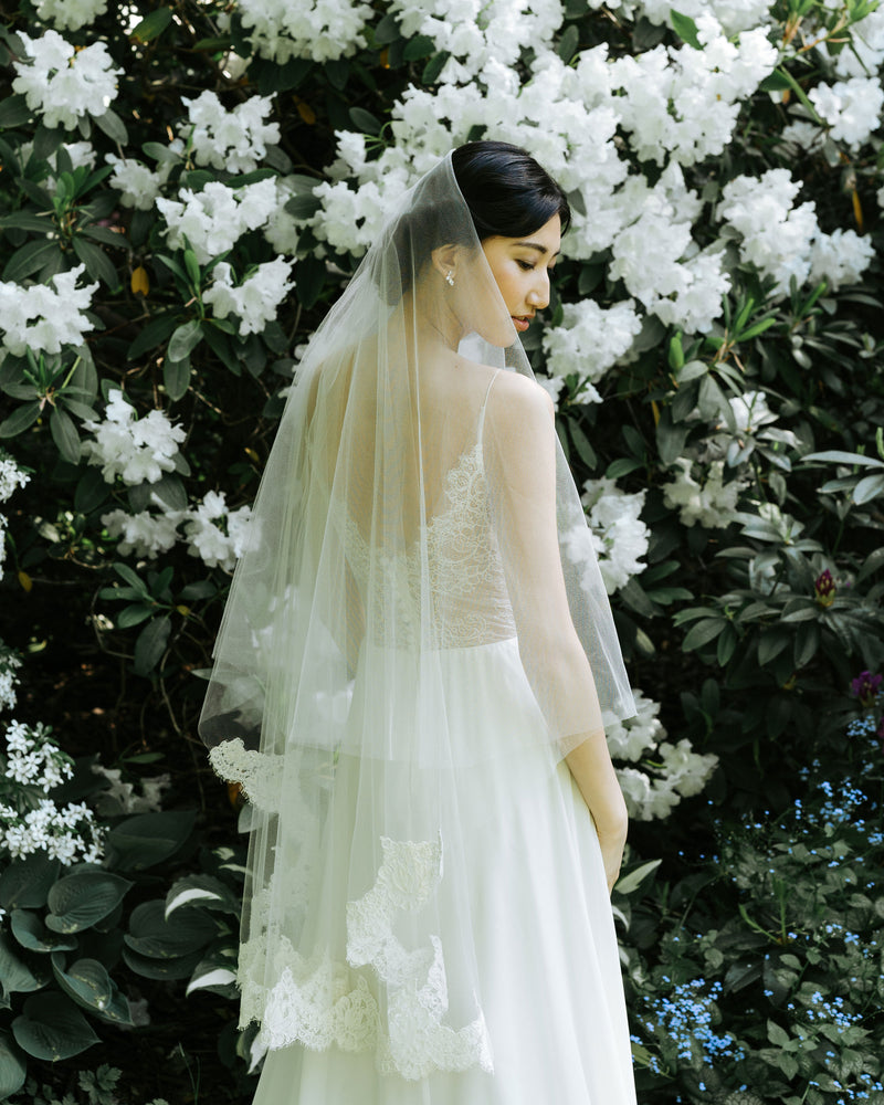 A model wears the Azalea two-layer veil with lace border on bottom layer and soft blusher worn to the back.