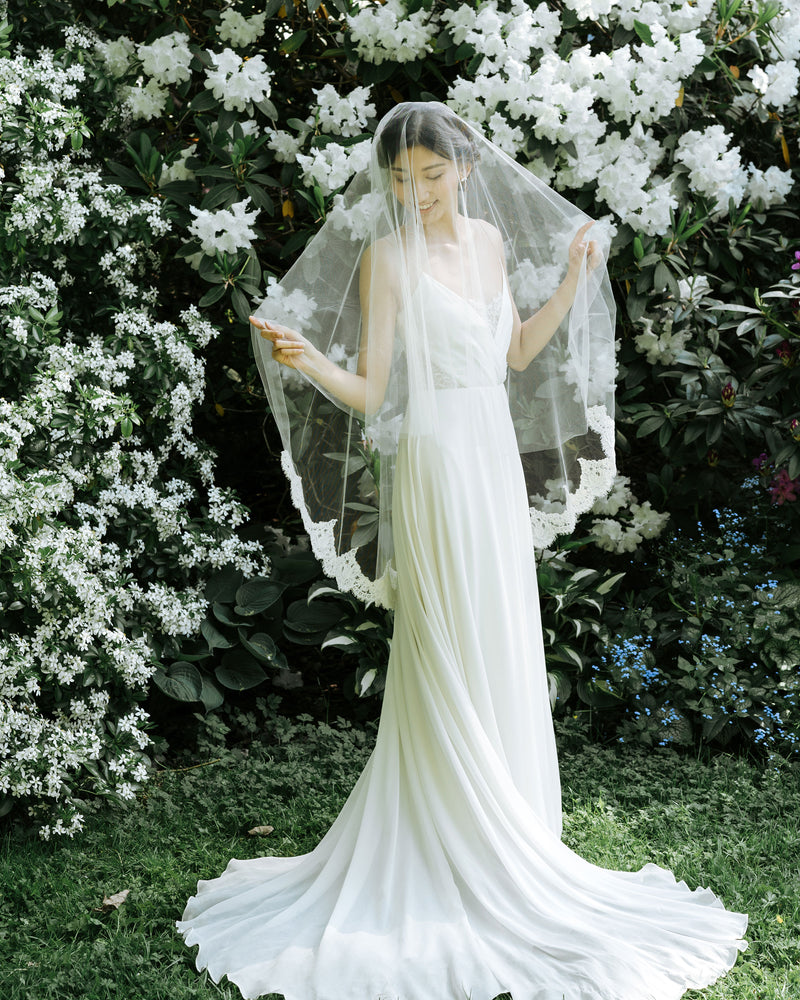 A model wears the Azalea two-layer veil with a lace border on the bottom layer and soft blusher worn to the front.