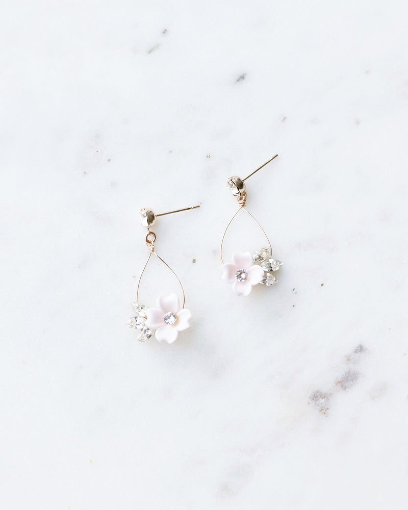 Flatlay of the all crystal vesion of the Belle Fleur Earrings. hand-crafted statement earrings with delicate wire teardrop. small blush flowers and crystals hanging from a crystal stud.