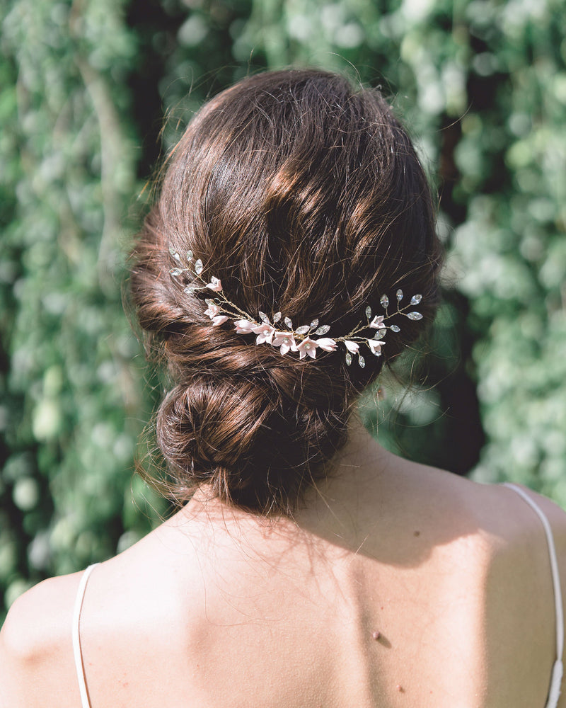Model with dark hair wearing the Belle Fleur Grand Comb above a low bridal updo. The comb is gold with blush flowers and lots of crystals.