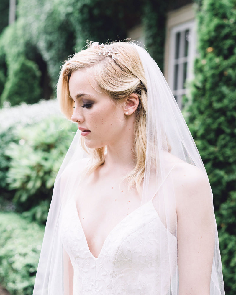 Model with blonde hair styled in loose waves, is wearing the Belle Fleur Grand Bridal hair Comb as a crown, paired with an airy tulle veil.