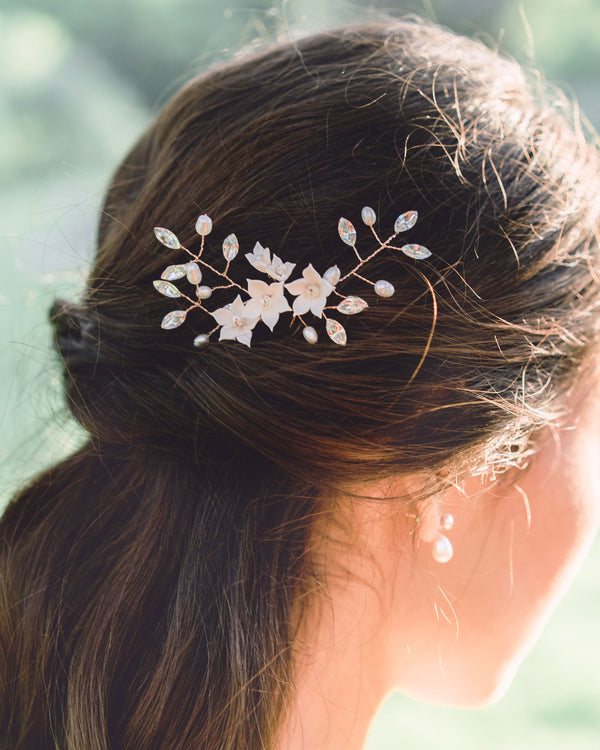 Model with dark hair wearing the Belle Fleur Hair pins in rose gold with blush flowers, crystals and freshwater pearls in a half updo bridal hair