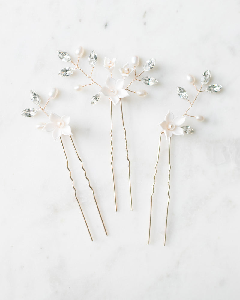 A flatlay view of the trio of Belle Fleur Hair Pins. The pins are gold, with ivory flowers, pearls, and crystals.