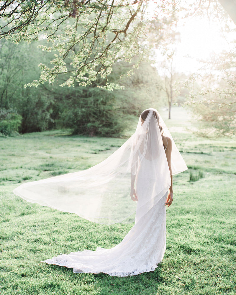 Model wearing calla chapel wedding veil with blusher and ribbon edge