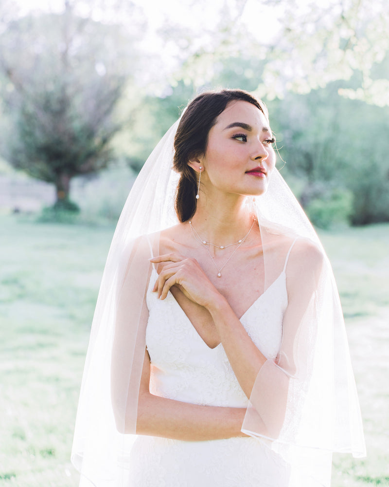 Model wearing calla chapel bridal veil with ribbon edge