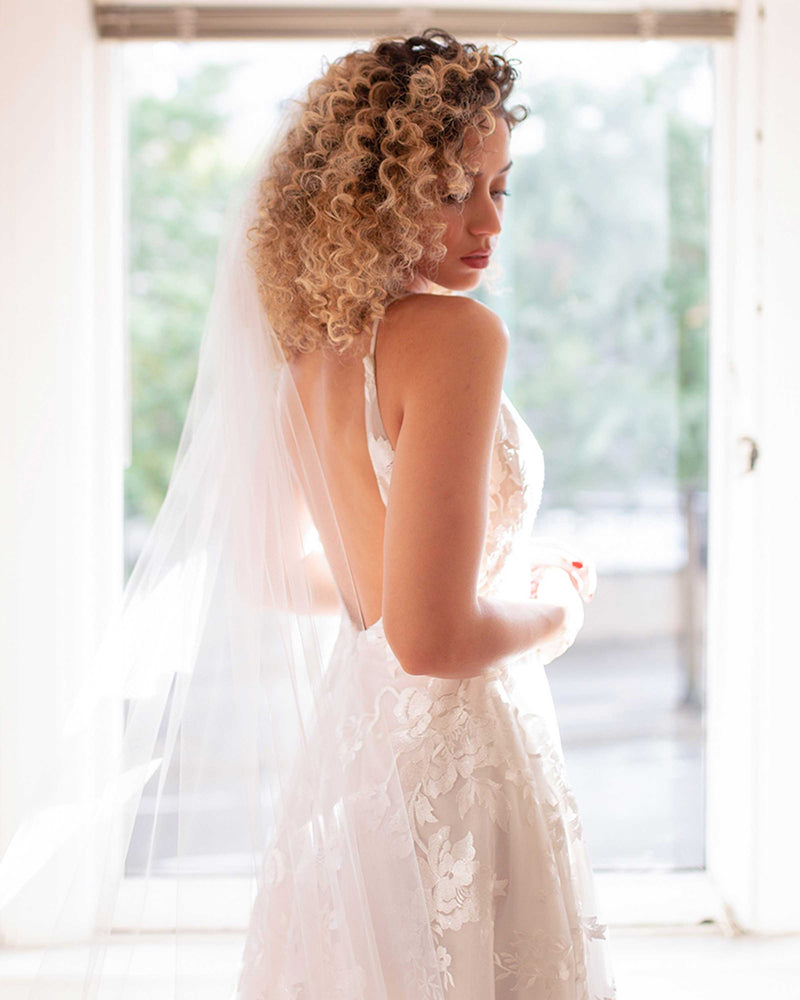 A bride wears the Camellia Luxe Lace Veil in extended chapel length.