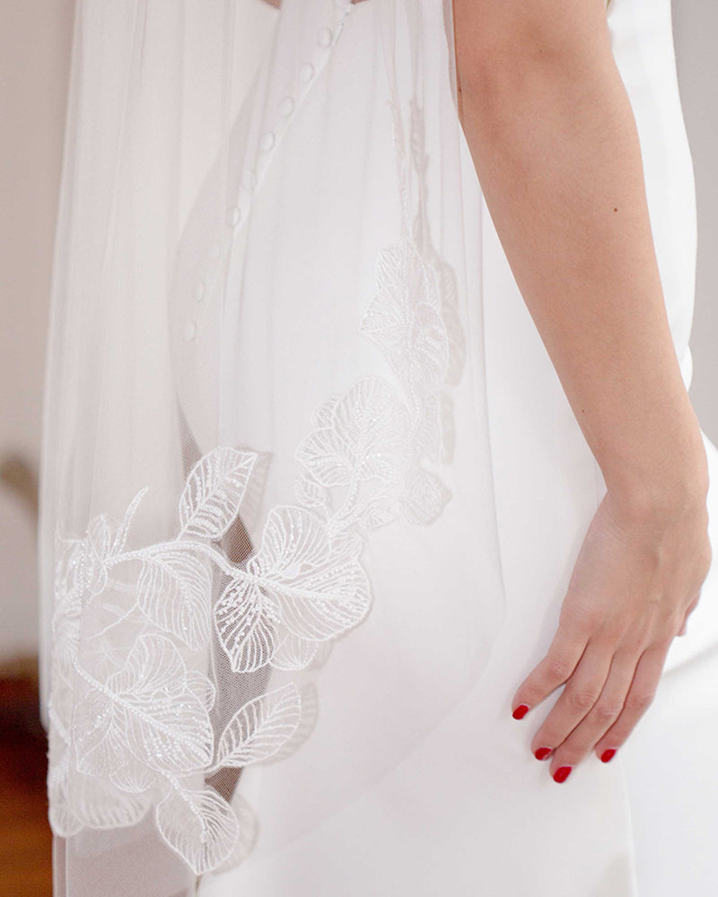 A close model view of the beaded lace on the Camellia Lace Veil in fingertip length.