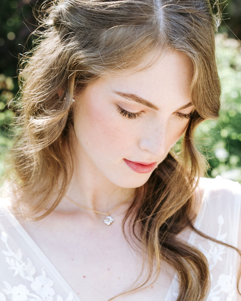 A model with auburn hair wears the Celestial Crystal Drop Necklace in gold