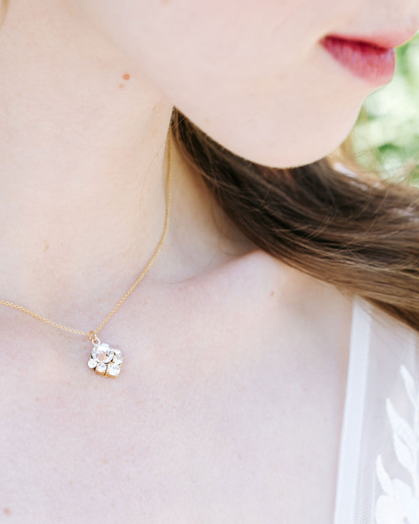 A close up view of a model wearing the Celestial Crystal Drop Bridal Necklace in gold with all crystal.