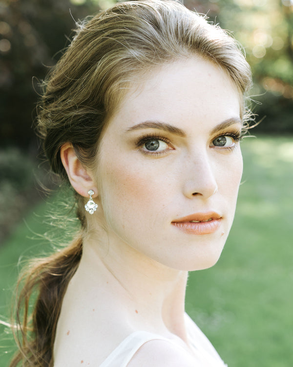 A model with a bridal hairstyle wears crystal drop bridal earrings in silver.