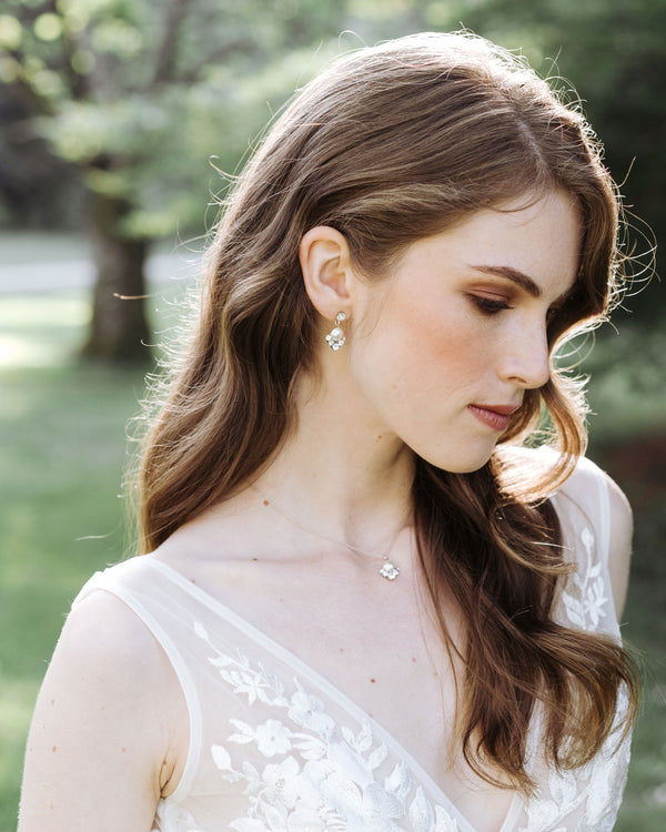 A model with auburn hair wears a wedding dress and the Celestial Pearl Drop Jewelry Set in silver with cream pearls.