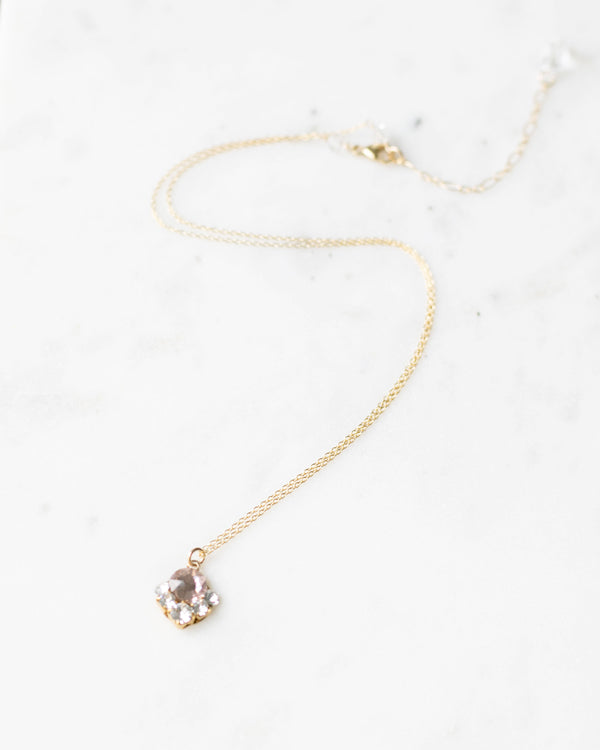 A flatlay view of the Celestial Crystal Drop Necklace in gold with blush crystals.