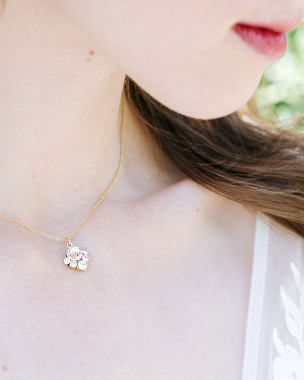 A close view on a model of the Celestial Crystal Drop Necklace in gold with a blush center crystal.