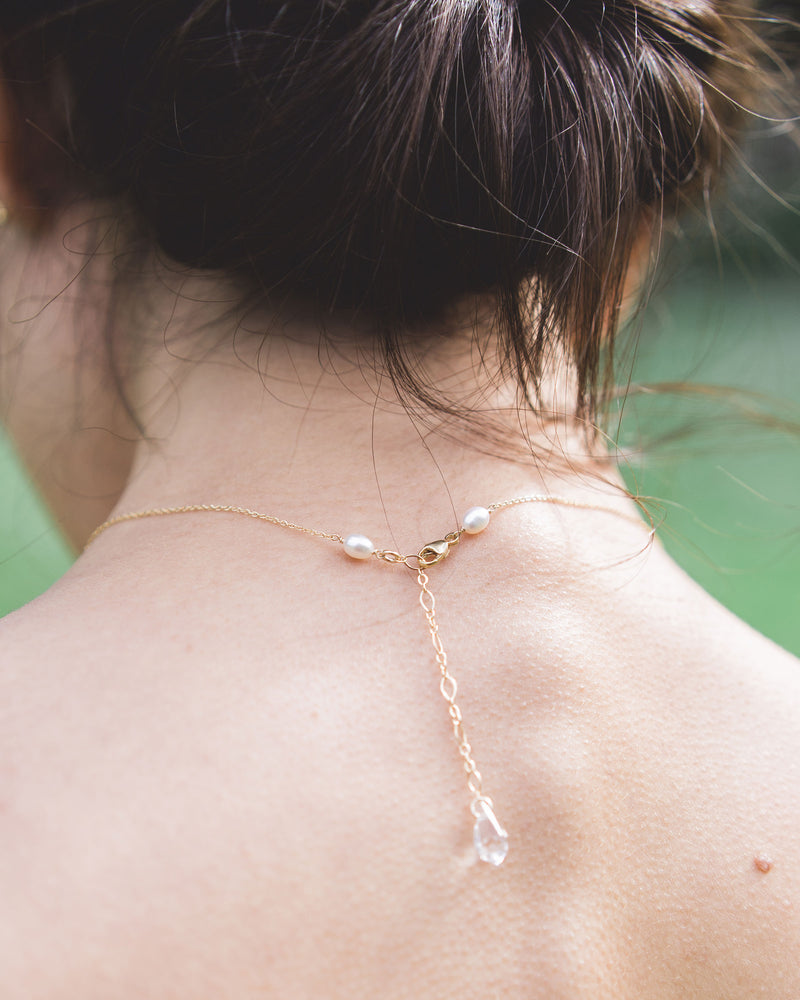 A back view of a model wearing our Celestial Pearl Drop Necklace, showing the dainty crystal drop at the back.