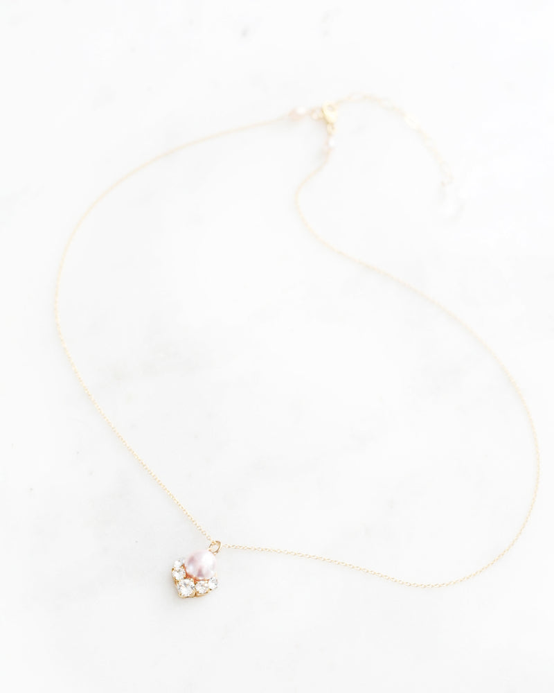 A flatlay view of the Celestial Pearl Drop Necklace in gold with a blush pearl.