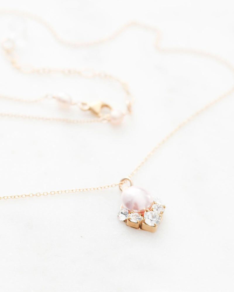 A flatlay view of the Celestial Pearl Drop Necklace in gold with a blush pearl.