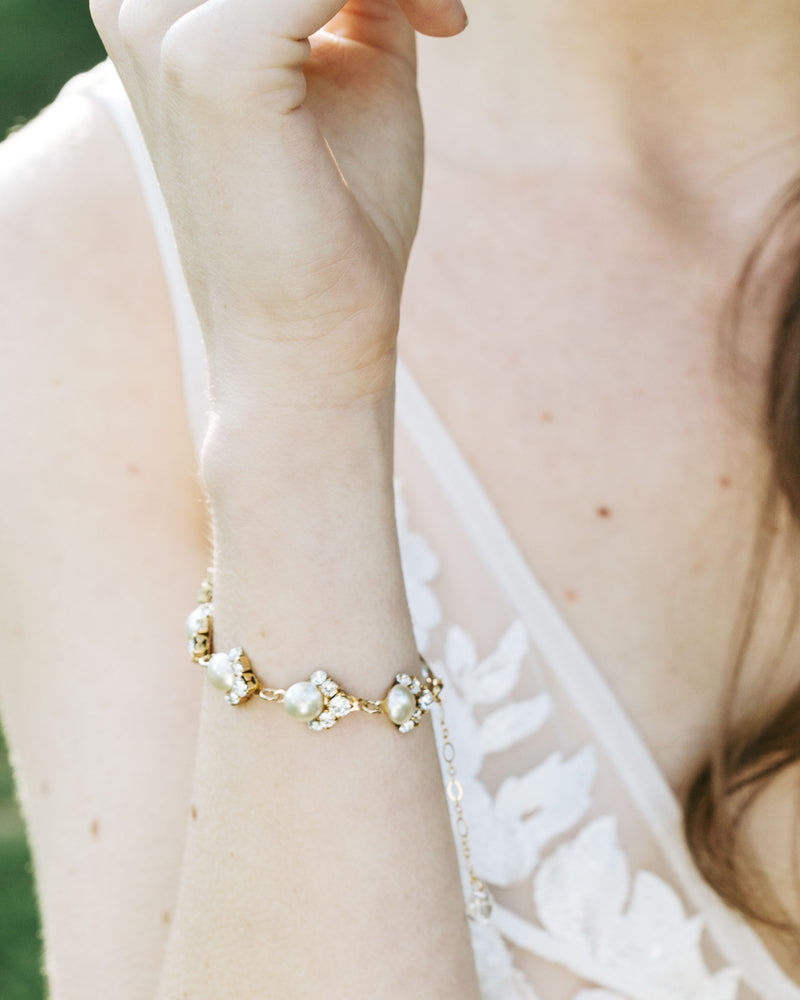 A close view of a model wearing the Celestial Pearl Cluster Bridal Bracelet in gold with cream pearls.