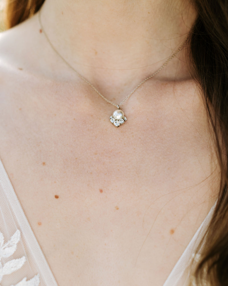 A close model view of the Celestial Pearl Drop Necklace in silver with a cream center pearl.