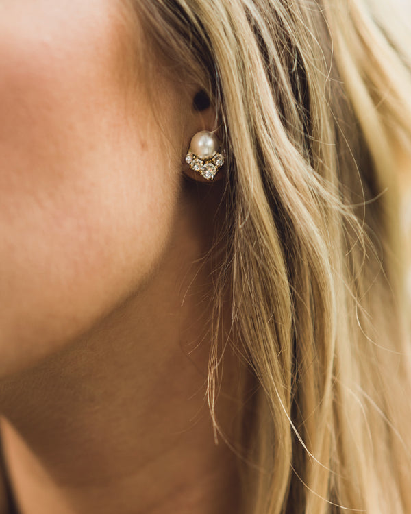 A close view of a blonde model wearing the Celestial Pearl Cluster Earrings in gold with cream pearls.